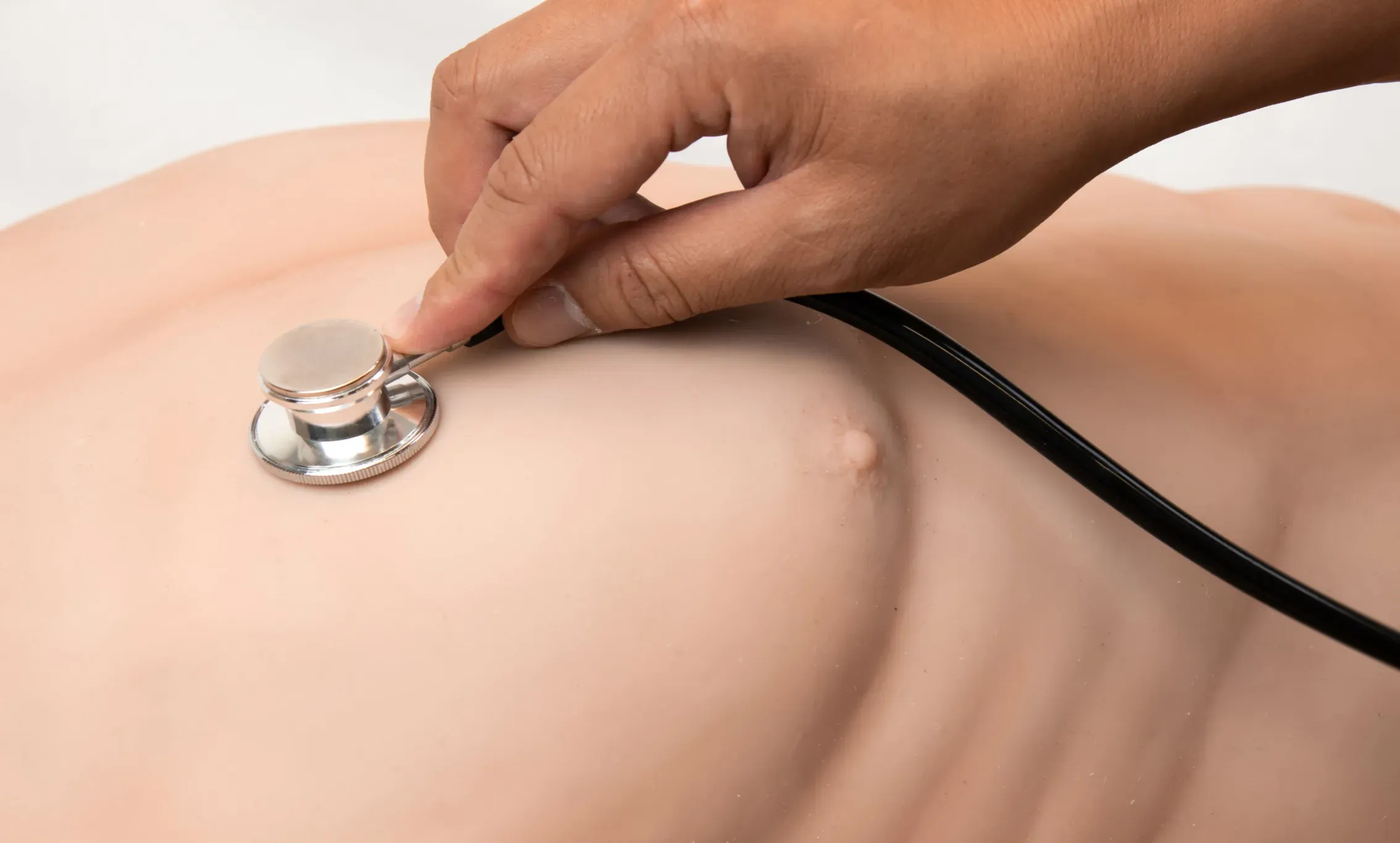 Auscultación con estetoscopio sobre el tórax de un simulador médico.