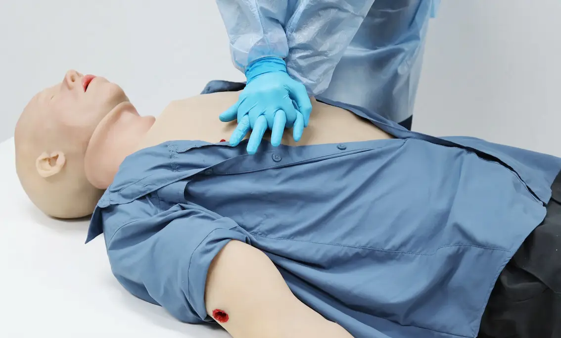 Simulador de reanimación con compresiones torácicas sobre paciente con heridas.