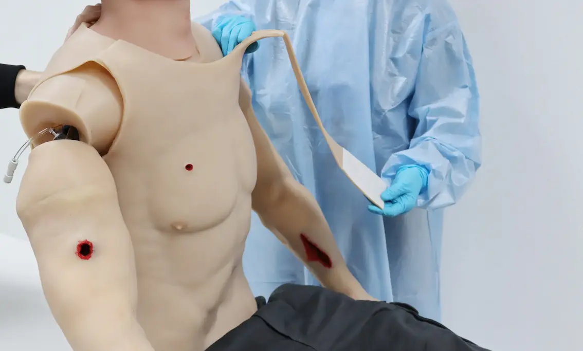 Simulador de torso con heridas de bala y parches de entrenamiento para trauma.